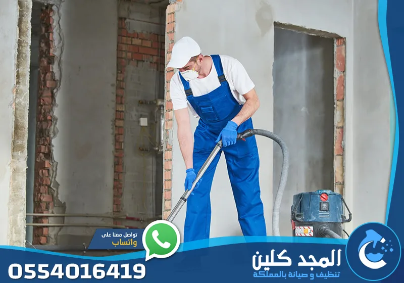 تنظيف بعد التشطيب الرياض 0554016419 المجد كلين عامل يقوم بكنس وتجميع ركام ومخلفات تكسير الحوائط في الغرفة بمكنسة يدوية.