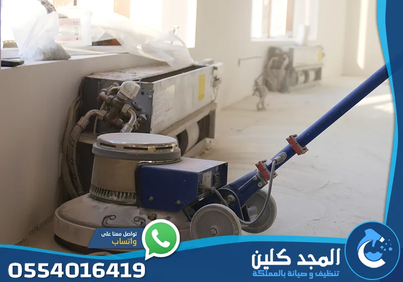 تنظيف مخلفات البناء الرياض 0554016419 المجد كلين لقطة قريبة لماكينة جلي وتلميع الأرضيات، مع معدات تكييف في الخلفية.